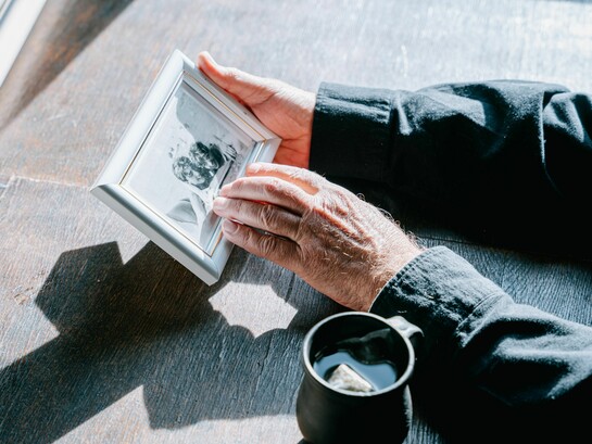 Hands holding a framed photograph, symbolizing remembrance, nostalgia, and the enduring bond with loved ones who have passed away