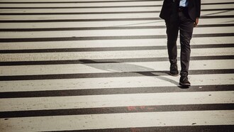 Homem cruza a rua na faixa de pedestres