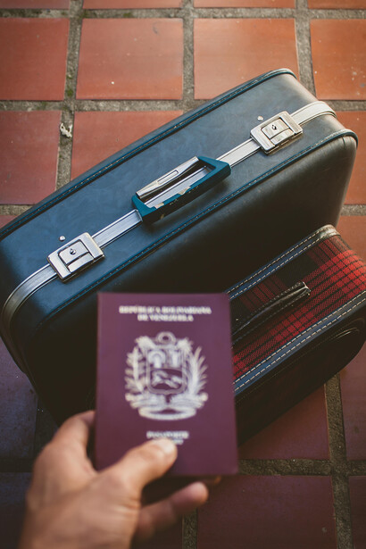 Mérida, Venezuela, a Venezuelan passport rests on a leather suitcase secured with a lock, symbolizing the limitations of a weak passport