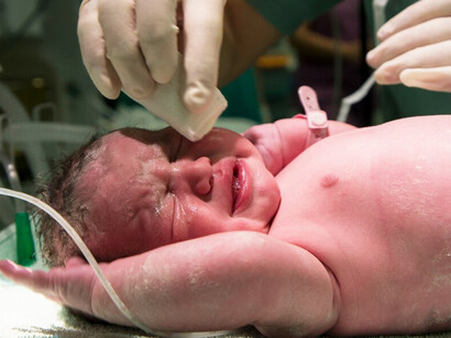 A close-up shot of a newborn baby crying, capturing their expressive features