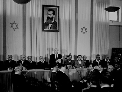 Ben Guirón proclama la creación del Estado de Israel bajo un retrato de Theodor Herzl, fundador del sionismo moderno (1948)