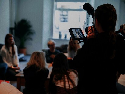 A female director is shooting a scene in the daytime as a tool to help lower the costs of lighting during the filmmaking process