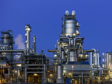 A large-scale industrial facility operating against the evening sky, representing the importance of industrial infrastructure and resources