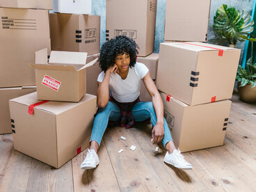A happy woman sitting on the floor surrounded by boxes in her new home