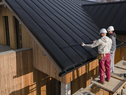 Roofers in safety helmets collaborate on the construction of a portable house