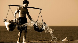 Uomo che tiene in equilibrio sulle spalle due ceste cariche: "Questo tempo moderno ci permette di vivere vite comode e di assecondare la gratificazione immediata, eppure senza impegno, senza fatica, senza sacrificio non c’è crescita"