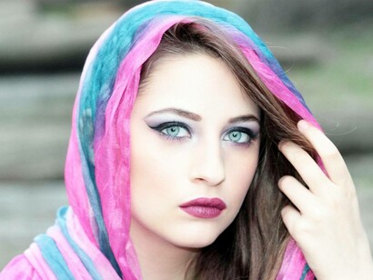 A woman wearing a scarf is staring at something at a distance with her light green eyes after her Keratopigmentation procedure