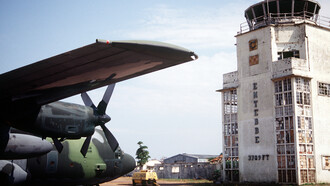 Un C-130 Hercules en frente a la antigua terminal del Aeropuerto de Entebbe: todavía son visibles los agujeros de bala del rescate en 1976