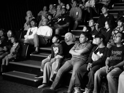 A monochrome image of people watching a film in a theater