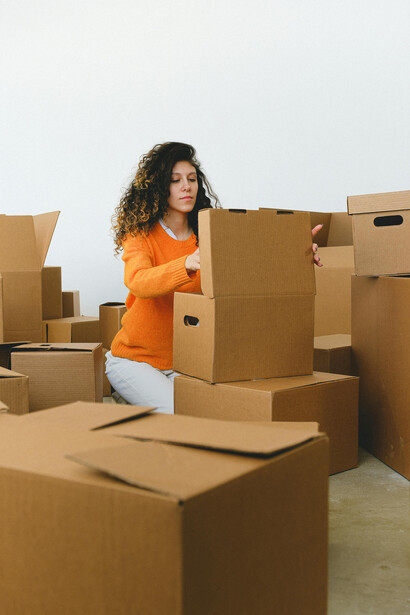 A young woman packs and arranges moving boxes as she begins a new chapter