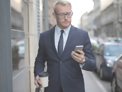 In a sharp suit, the man strides down the road, his face lighting up with happiness as he takes in the positive news delivered over the phone