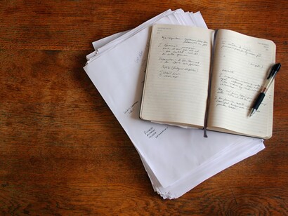 Un cuaderno, hojas de papel y un bolígrafo