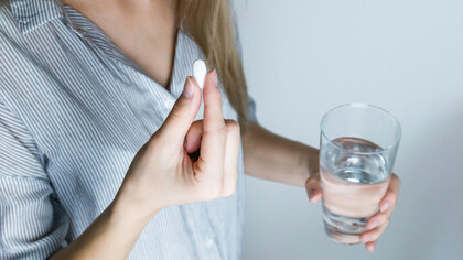 Pessoa busca um copo d'àgua para tomar um remédio anti-inflamatório