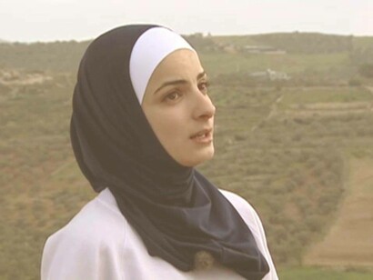 A Palestinian woman reciting the poems of Mahmoud Darwish in a field