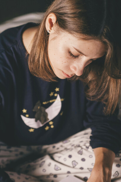 A young woman journaling on her bed in a relaxed, cozy atmosphere, immersed in her thoughts