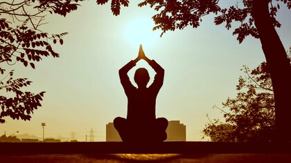 A silhouette of a person practicing yoga at sunrise, surrounded by nature’s tranquility