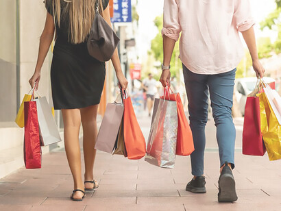 Gracefully navigating the scene, a woman and a man strolling hand in hand, each clutching a collection of fashionable shopping bags