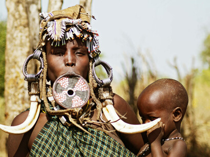 Mursi woman with her child. They start inserting wood billets into the lip, each time making them larger and more noticeable