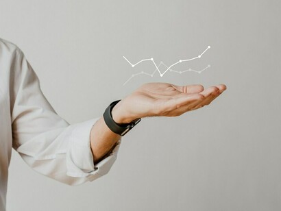 A digital bar graph showing increasing growth is overlaid with a businessman’s hand, representing the connection between strategic decision-making and successful financial outcomes