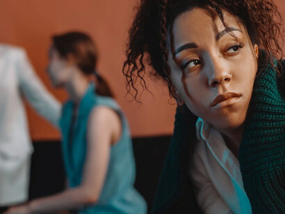 A lone black woman stands isolated, facing two white women