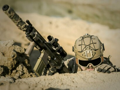 Soldier holding firearm while keeping a vigilant lookout, symbolising the uncertainty of the modern warfare