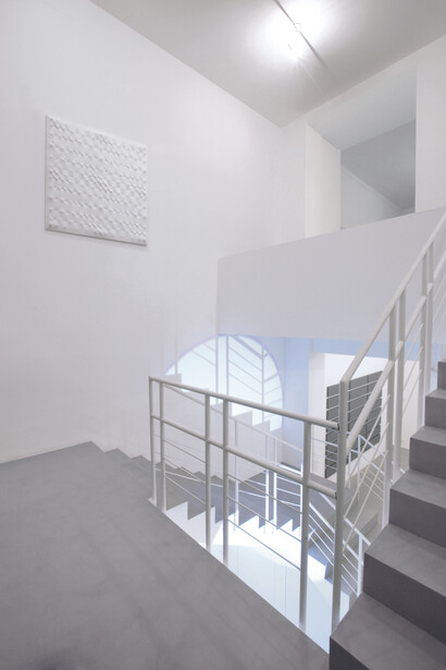 (dall’alto verso il basso) Enrico Castellani,
Superficie bianca, 1990 Acrilico su tela estroflessa, 120x120 cm. Michel Verjux, Contre-plongée traversante, à l’escalier (source au sol), 2015 Proiettore. Alan Charlton, 24 Horizontal parts, 2010 Acrilico su tela, 211,5x319,5 cm. Veduta parziale dell’esposizione A arte Invernizzi. Courtesy A arte Invernizzi, Milano. Foto Bruno Bani