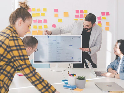 Confidently standing behind a sleek flat-screen computer monitor, the man passionately discusses the intricacies of content marketing, captivating his audience with insights and strategies that ignite their enthusiasm for effective brand storytelling