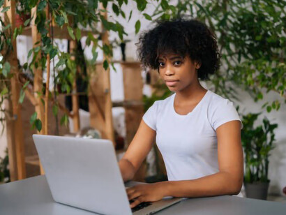 A female freelance designer, immersed in a biophilic design environment, actively explores and generates fresh ideas, meticulously crafts a business plan, and works remotely on her laptop