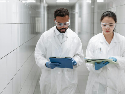 In a modern innovation lab, a man and woman walk through the hallway as scientists collaborate on research and development projects
