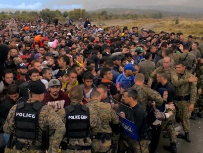 Una barrera de policías trata de impedir el avance de los inmigrantes