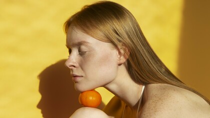 A woman with naturally freckled skin in warm daylight, reflecting the importance of protecting vulnerable skin from UV damage