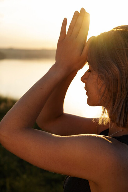 In a serene natural setting, a woman meditates, channeling spiritual energy and inner strength, surrounded by a vibrant energy field