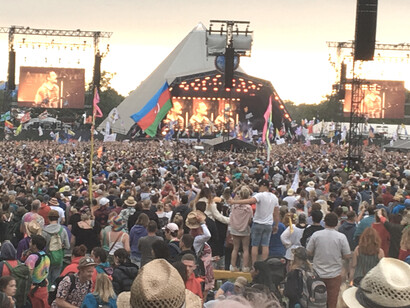 A vibrant crowd standing before the stage at Glastonbury Festival in England, capturing the spirit of music and togetherness