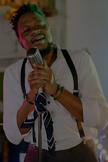 A dynamic figure takes center stage, wielding a microphone with flair, as he enthralls the audience with an energetic and captivating concert performance