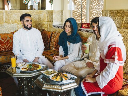 Young people sharing a meal in a richly decorated traditional setting, representing hospitality as a bridge between cultures