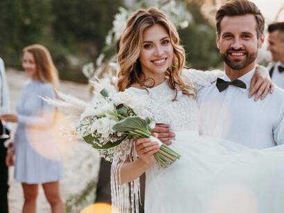 Beachside wedding with the bride and groom surrounded by happy guests, enjoying a picturesque and lively seaside ceremony