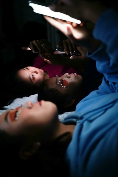 Young women lying on a bed, focused on their phones