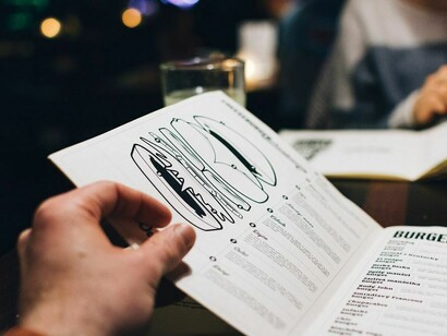 Hands gripping a menu tightly as diners scan a long list of dishes, caught in the stress of decision-making