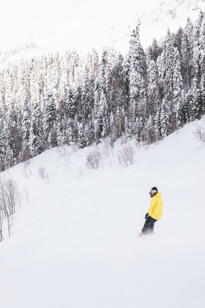 A woman snowboarding in the mountain snow, with confidence