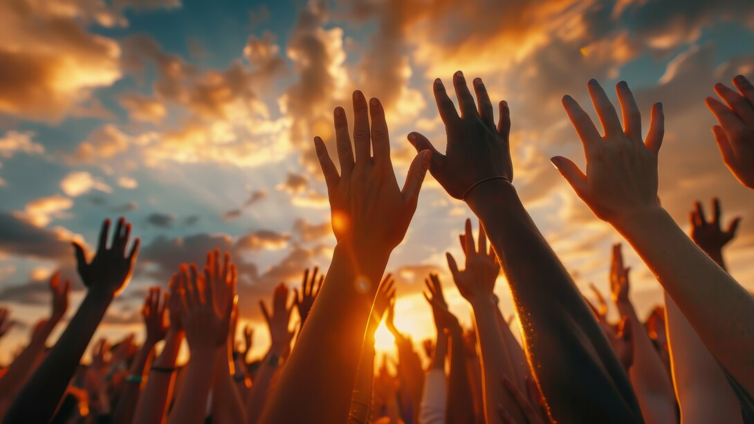 A diverse group of hands reaches upward against a dramatic sunset sky, symbolizing a call for justice and equality