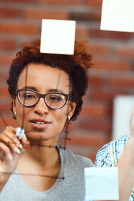 Two colleagues collaborate to brainstorm ideas, using sticky notes to capture each potential solution as they work through the problem-solving process