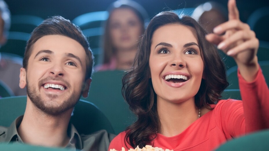 Una pareja en el cine hablando y comiendo palomitas