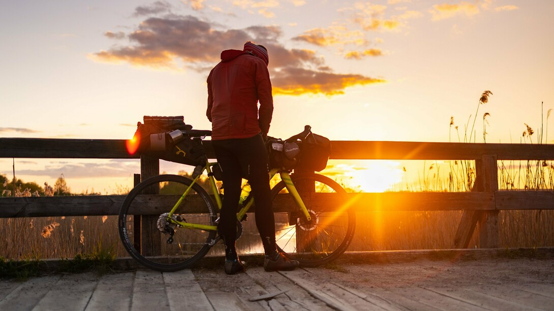 A bicycle traveler enjoying a peaceful sunset, representing low-carbon travel that connects people more closely with nature