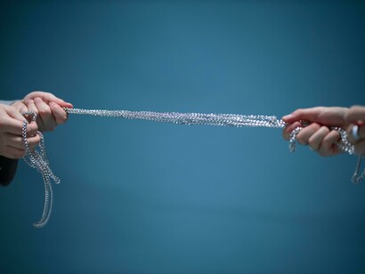 Hands pulling over a silver chain to express stress among different perspectives