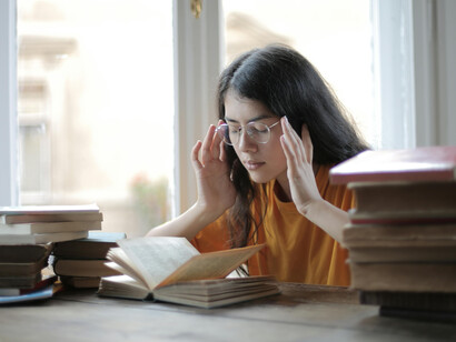 A weary female student holding her head, visibly overwhelmed and fatigued