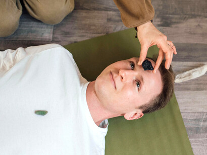 In a calming reiki session, a crystal is gently placed on the forehead to align and restore energetic flow