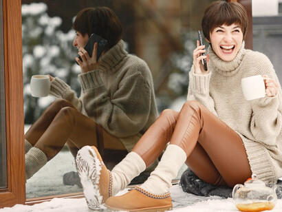 A woman in a cozy white sweater enjoys a warm cup of tea, surrounded by the serene beauty of winter's landscape