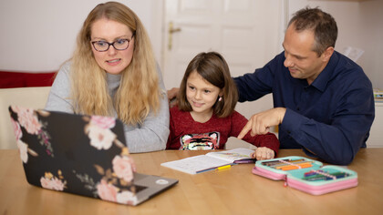 Pai e mãe ajudam a filha a fazer uma tarefa de casa enquanto também pensam em mudar a forma de contribuir para o aprendizado