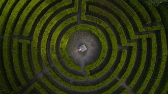 A person standing at the heart of a vast maze, symbolizing humanity’s struggle to maintain direction during times of uncertainty