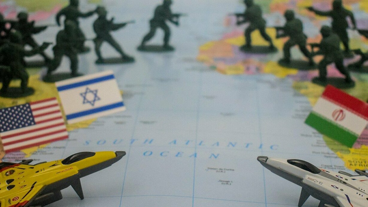 Soldados de brinquedo e bandeiras dos Estados Unidos, Israel e Irã sobre um mapa-múndi representam a disputa militar e geopolítica que envolve as três potências. A escalada no Oriente Médio transforma uma rivalidade regional em uma crise com potencial para afetar alianças, mercados e o equilíbrio estratégico internacional